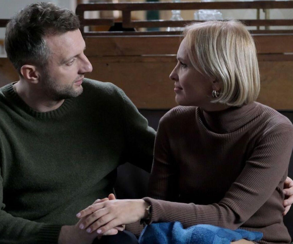 Para, Dorota (Iwona Rejzner) i Bartek (Arkadiusz Smoleński), siedząca na kanapie i trzymająca się za ręce. Mężczyzna w zielonym swetrze, kobieta w brązowym swetrze, oboje patrzą na siebie z troską, co nawiązuje do wyzwań w ich życiu w serialu M jak miłość. Więcej na Super Seriale.