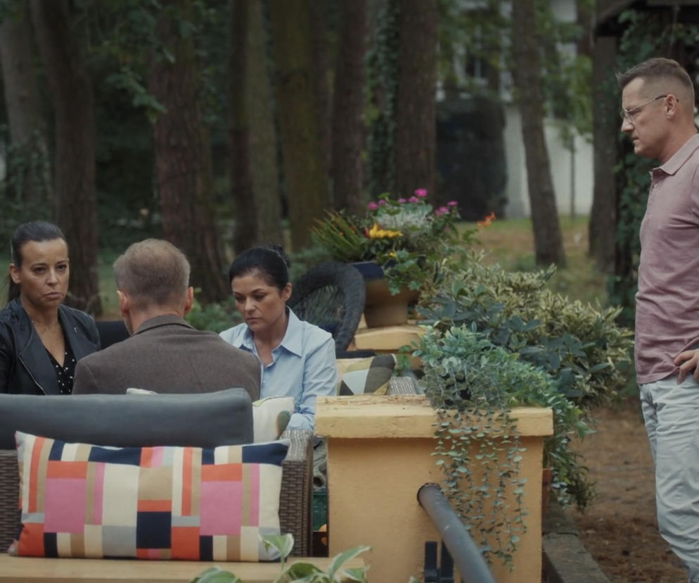 Piotrek Zduński z M jak miłość stojący na zewnątrz, podczas gdy Magda i Andrzej Budzyńscy siedzą w ogrodzie. Piotrek informuje o kontakcie z Pawłem po śmierci Franki, co można przeczytać na Super Seriale.