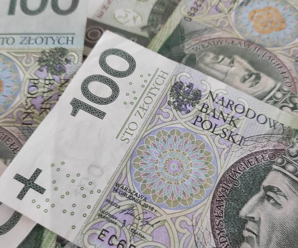 Banknoty o nominale sto złotych ułożone jeden na drugim. O kontroli przelewów przez skarbówkę przeczytasz na Eska.