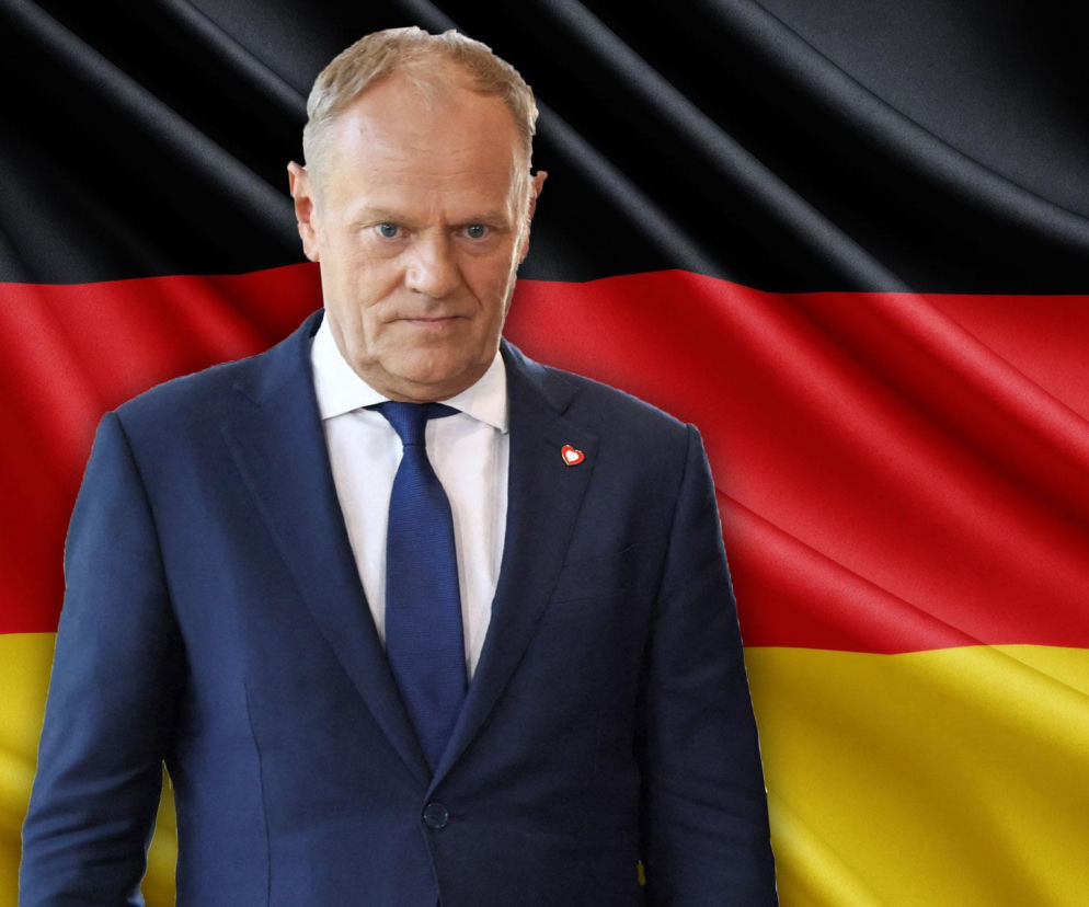 Donald Tusk w granatowym garniturze i krawacie na tle falującej flagi Niemiec. W tle widać czarny, czerwony i złoty pas. Zdjęcie symbolizuje polsko-niemieckie porozumienie dotyczące darmowych biletów kolejowych dla młodych, o czym przeczytasz na portalu Super Biznes.