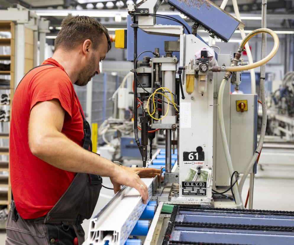 Pracownik fabryki Redan obsługuje maszynę do produkcji okien PVC. O procesie produkcji przeczytasz na Muratordom.