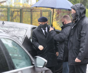 Pięciu ochroniarzy prowadzi Kaczyńskiego do bramy