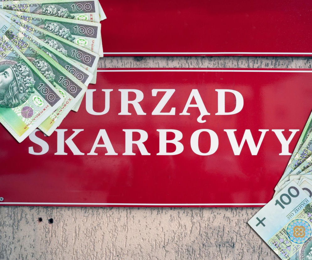 Czerwona tablica z napisem Urząd Skarbowy otoczona banknotami o nominale sto złotych. O licytacjach aut na SE Superbiz.