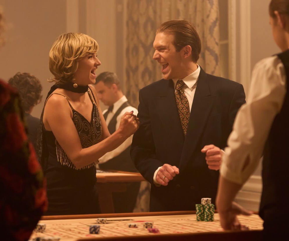 Zuza (Waleria Gorobets) i Budyń (Piotr Witkowski) z serialu Wojna zastępcza zadowoleni przy stole do ruletki. Zuza ma na sobie błyszczącą sukienkę, Budyń garnitur i krawat. Ich radosne miny nawiązują do ryzykownej misji w Berlinie, o której można przeczytać na Super Seriale.