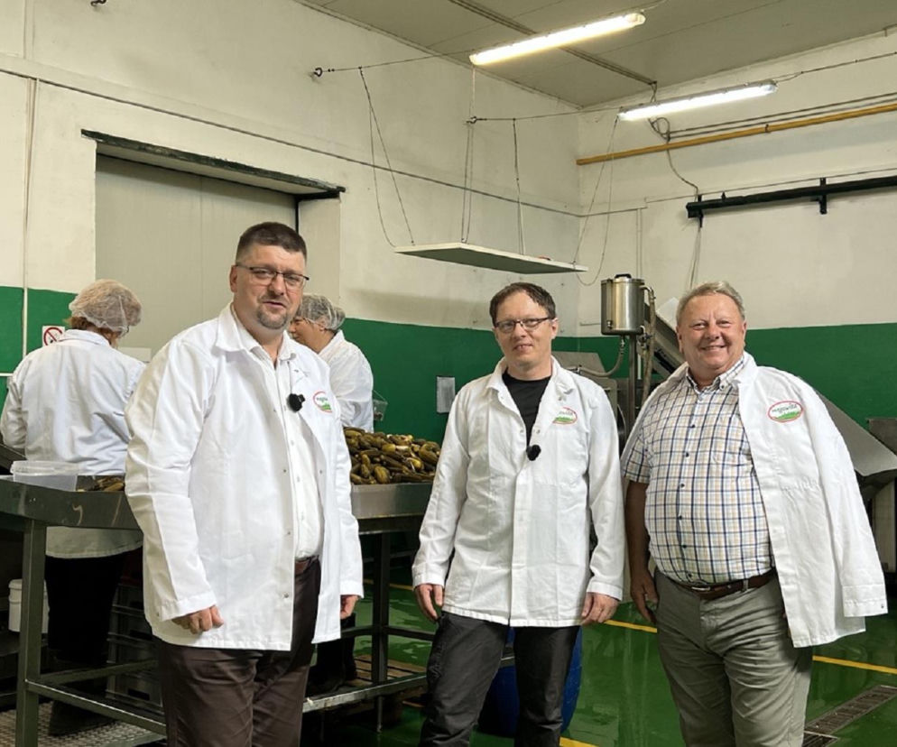Trzej uśmiechnięci mężczyźni w hali produkcyjnej firmy Megawita. O wsparciu dla firm przeczytasz na Eska Starachowice.