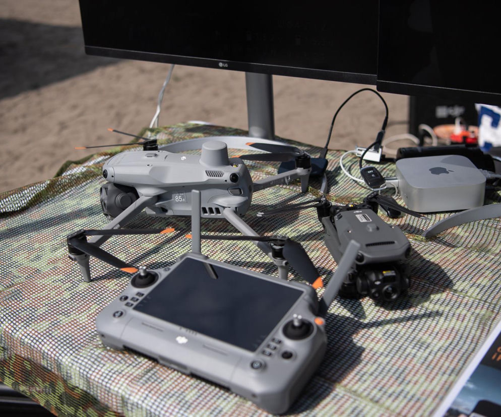Dwa szare drony, kontroler z ekranem i sprzęt komputerowy na stole. O technologiach antydronowych pisze SE Portal Obronny.
