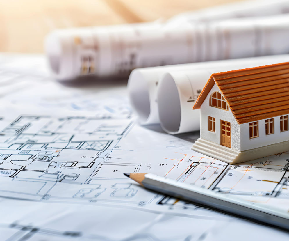 Model małego białego domu na planach architektonicznych z ołówkiem. O projektowaniu sieci w domu pisze Muratordom.