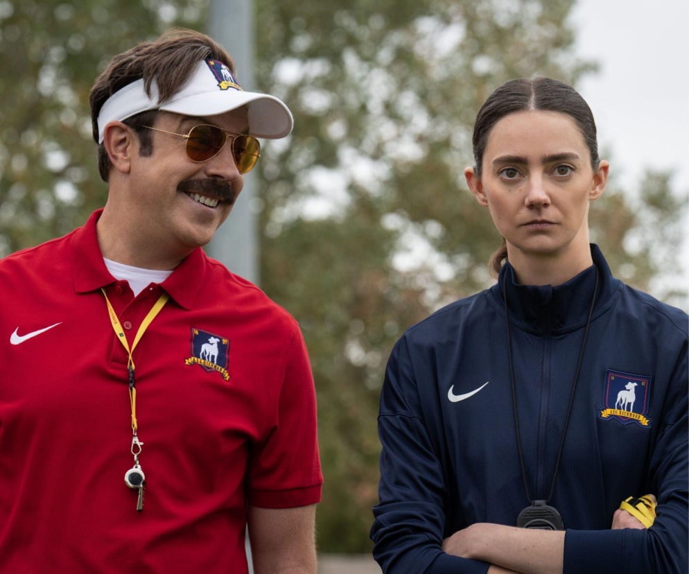 Uśmiechnięty Ted Lasso w okularach i kobieta w sportowym stroju. O 4. sezonie serialu przeczytasz w serwisie Eska.