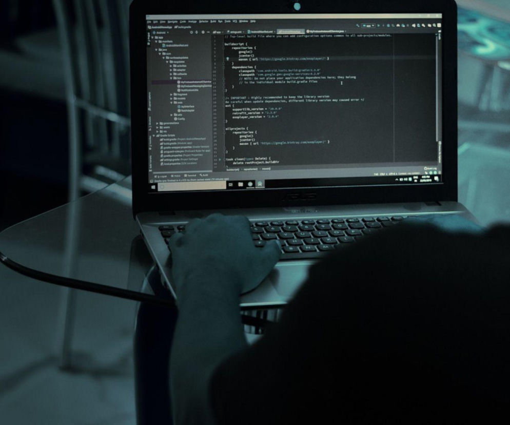 Osoba przy laptopie z widocznym kodem programistycznym na ekranie. O ataku hakerskim na MyDr przeczytasz w Eska.