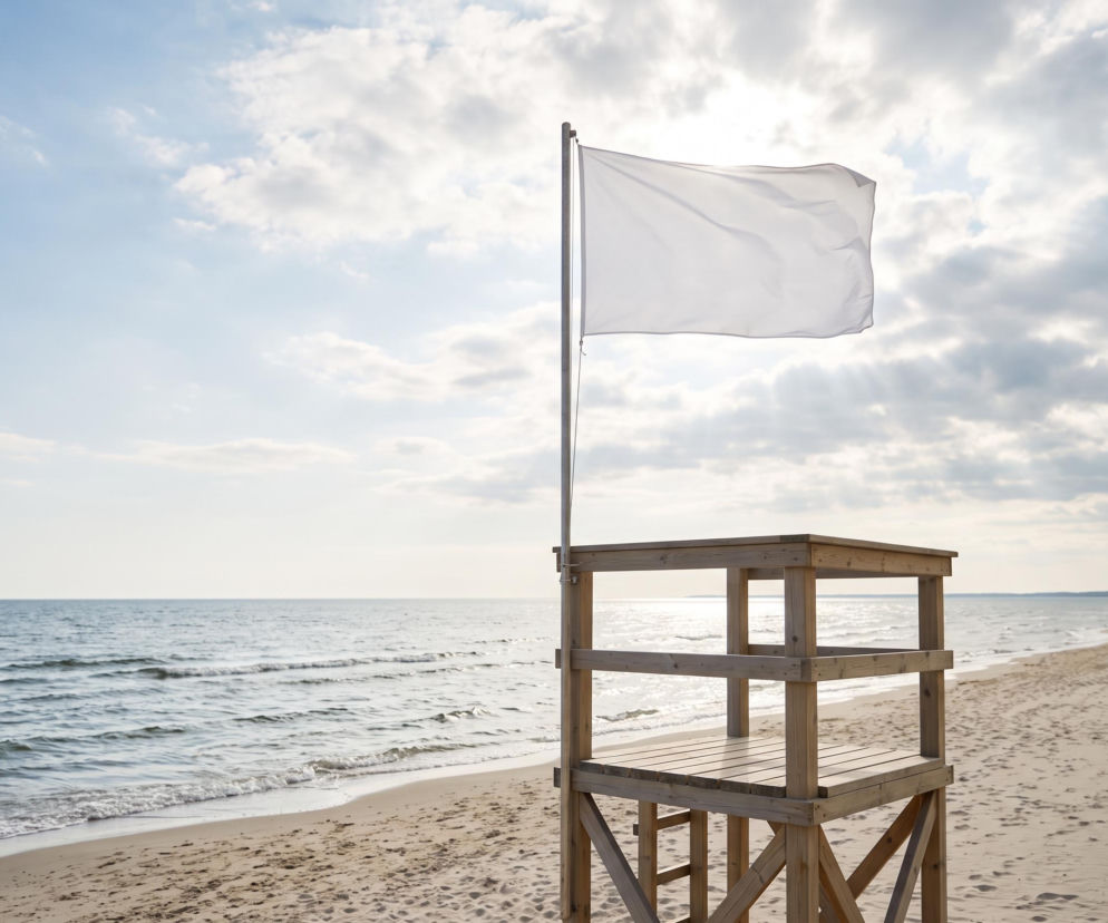 Biała flaga na wieży ratowniczej na pustej plaży w Świnoujściu. O warunkach na kąpieliskach przeczytasz na SE Szczecin.