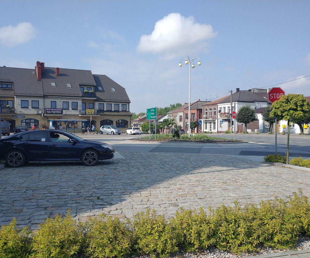 Plac w Książu Wielkim z widokiem na kamienice i czarny samochód. O tym małym mieście przeczytasz na Eska Kraków.