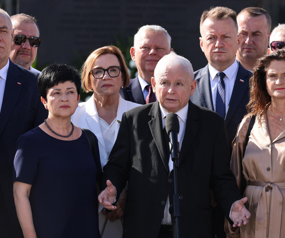 Jarosław Kaczyński przemawia do mikrofonu w otoczeniu polityków PiS. O miesięcznicy przeczytasz na SE Polityka.