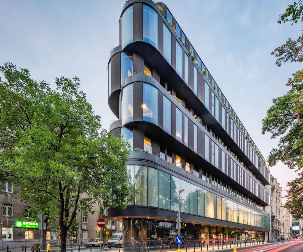 Nowoczesny budynek Nobu Hotel Warsaw z zakrzywionymi, przeszklonymi fasadami i zielenią na tarasach, wyróżnia się na tle miejskiej zabudowy Warszawy. Ten projekt Medusa Group to przykład współczesnej architektury, o której możesz przeczytać na portalu Architektura Murator Plus.