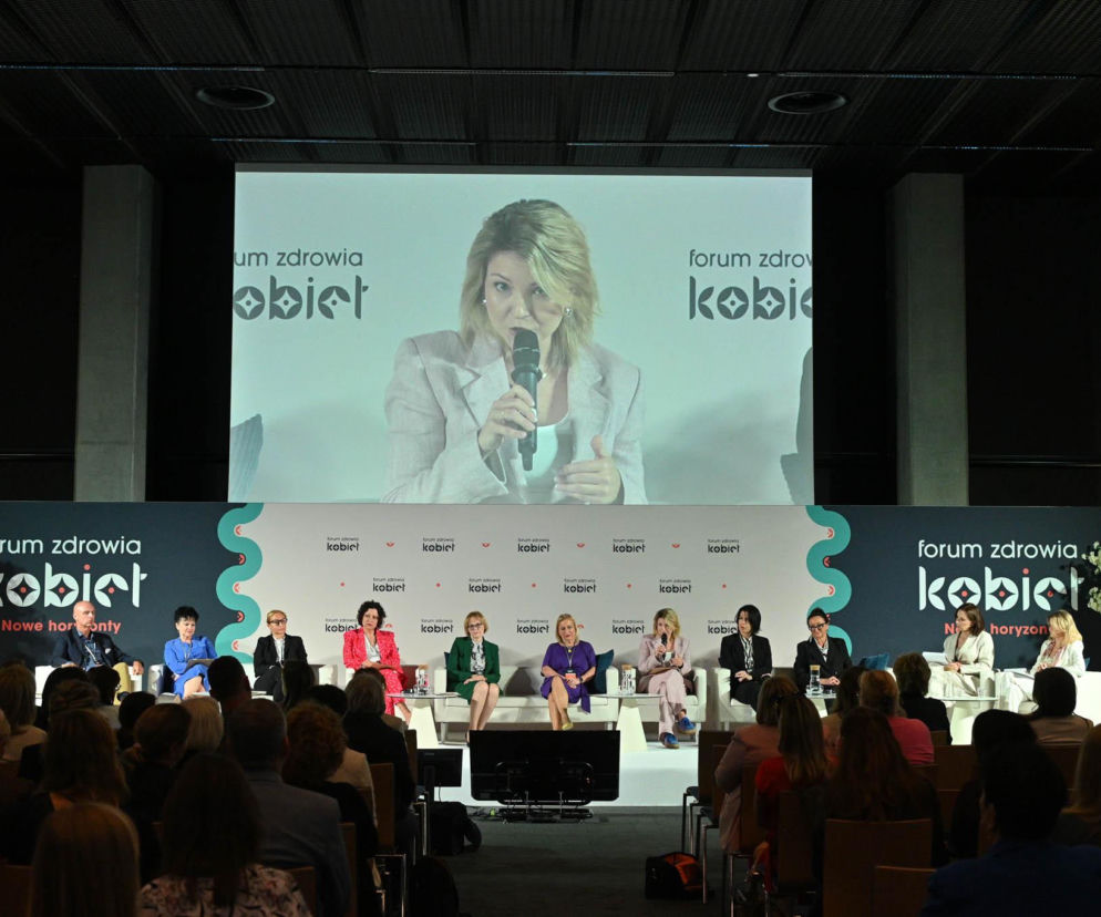 Kobiety uczestniczące w panelu dyskusyjnym Forum Zdrowia Kobiet w Katowicach, w tym prowadząca na ekranie, omawiają interdyscyplinarną współpracę dla zdrowia kobiet. Więcej o wyzwaniach i rozwiązaniach w opiece nad kobietą można przeczytać na portalu Poradnik Zdrowie.