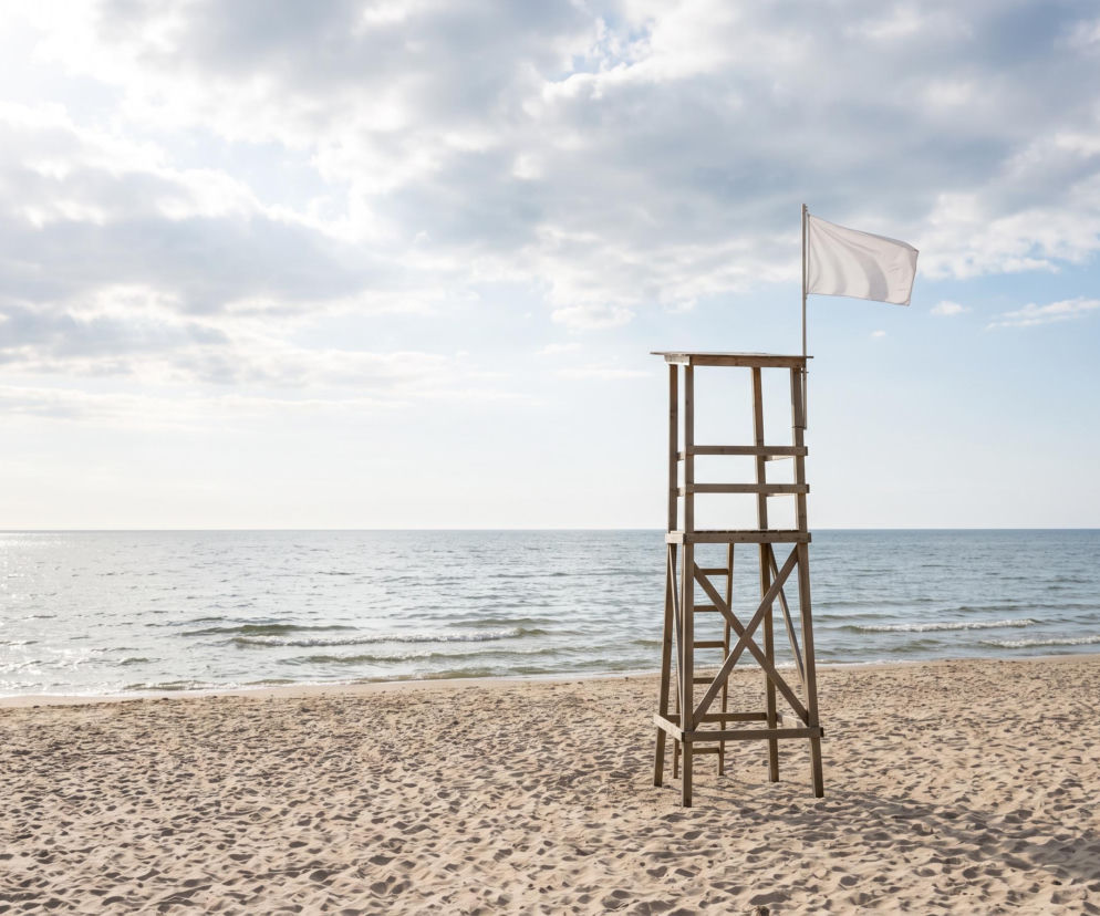 Drewniana wieża ratownika z białą flagą na plaży w Chłopach. O bezpiecznych kąpielach przeczytasz na SE Szczecin.