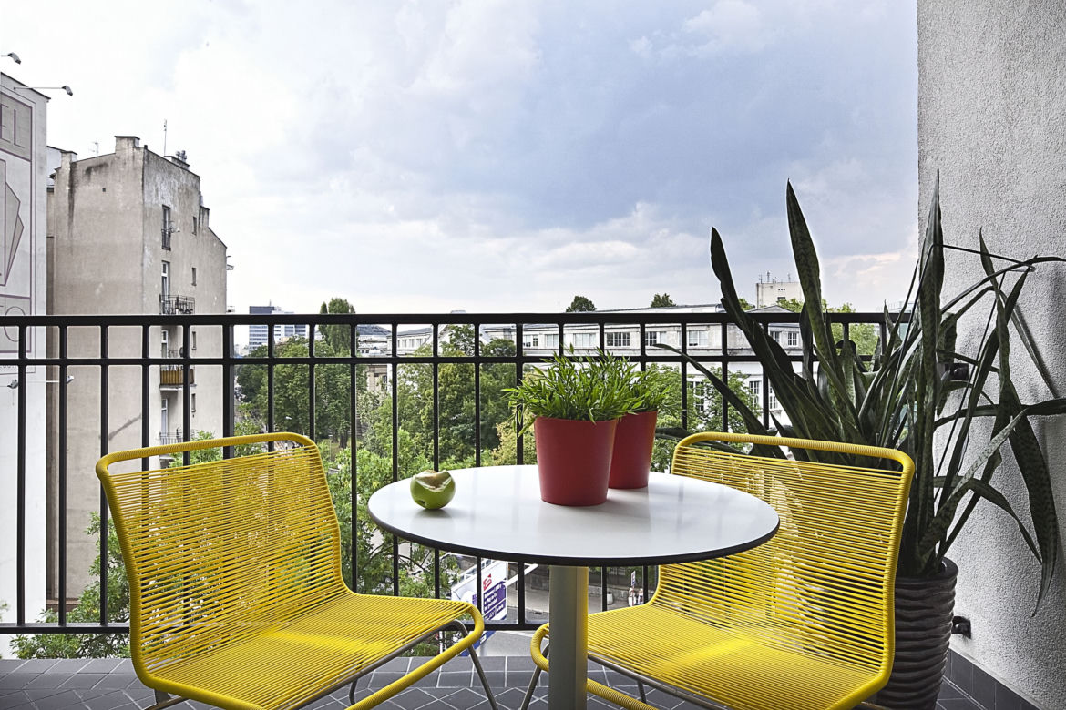Mały balkon w bloku lub kamienicy z akcentami koloru