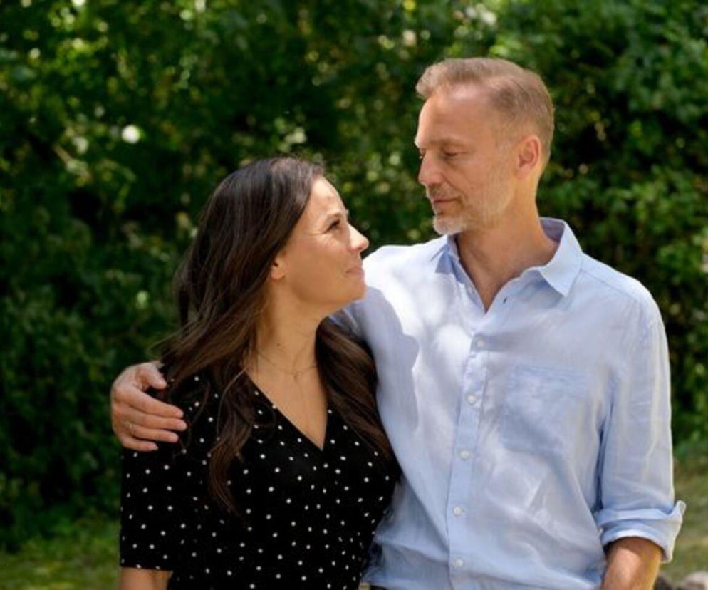 Anna Mucha jako Magda i Krystian Wieczorek jako Andrzej z serialu „M jak miłość” spoglądają na siebie czule na tle zielonych krzewów, co symbolizuje ich pożegnanie z Siedliskiem. Więcej o ich losach przeczytasz na portalu Super Seriale.