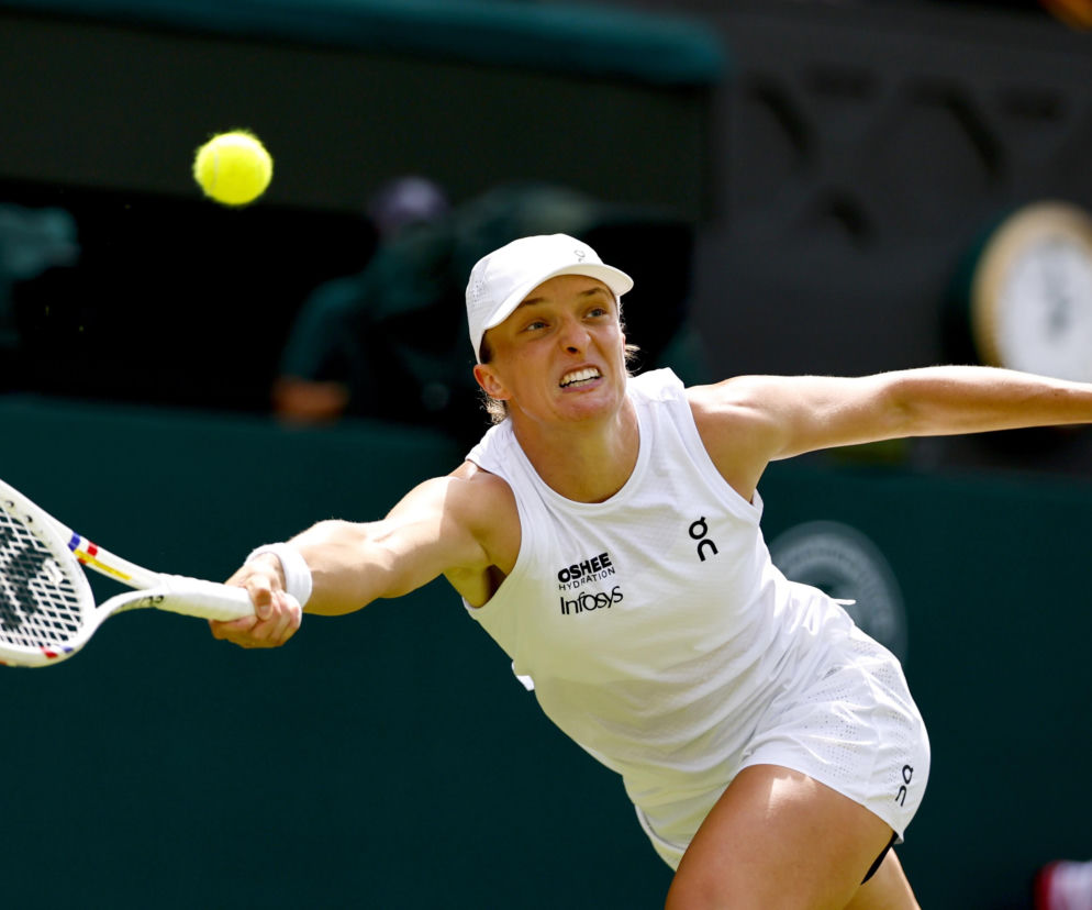 Iga Świątek uderza piłkę rakietą podczas meczu na Wimbledonie. O jej kolejnych meczach przeczytasz na SE Supersport.