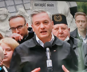 Robert Biedroń na tle religijnego hasła