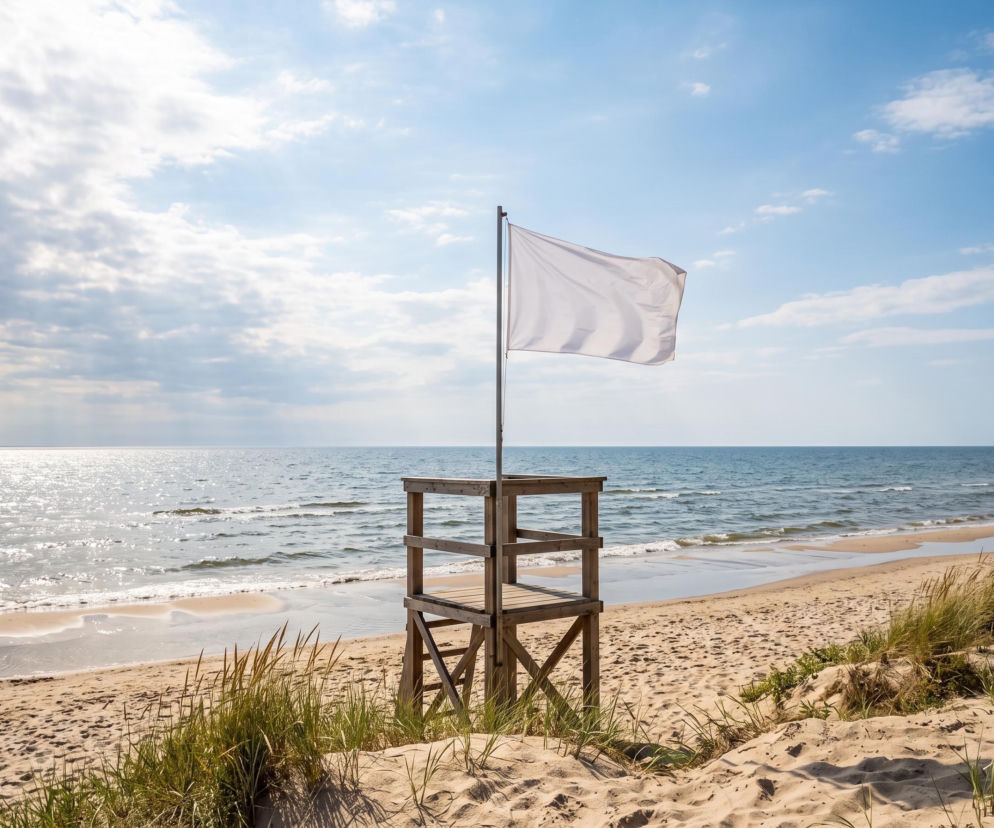 Biała flaga na wieży ratowniczej w Mrzeżynie przy pustej plaży. O pogodzie nad morzem przeczytasz na SE Szczecin.
