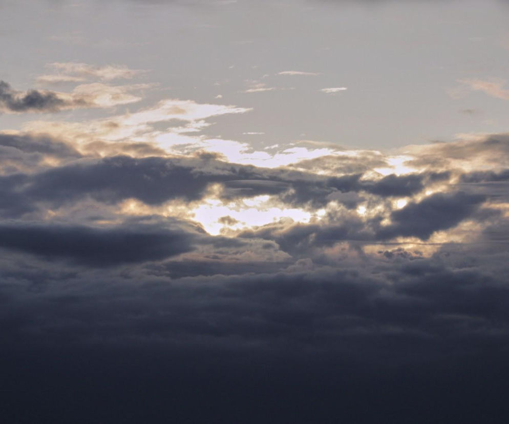 Ciemne, gęste chmury na niebie, przez które przebija się jasne światło słońca. O prognozie IMGW przeczytasz na SE Pogoda.