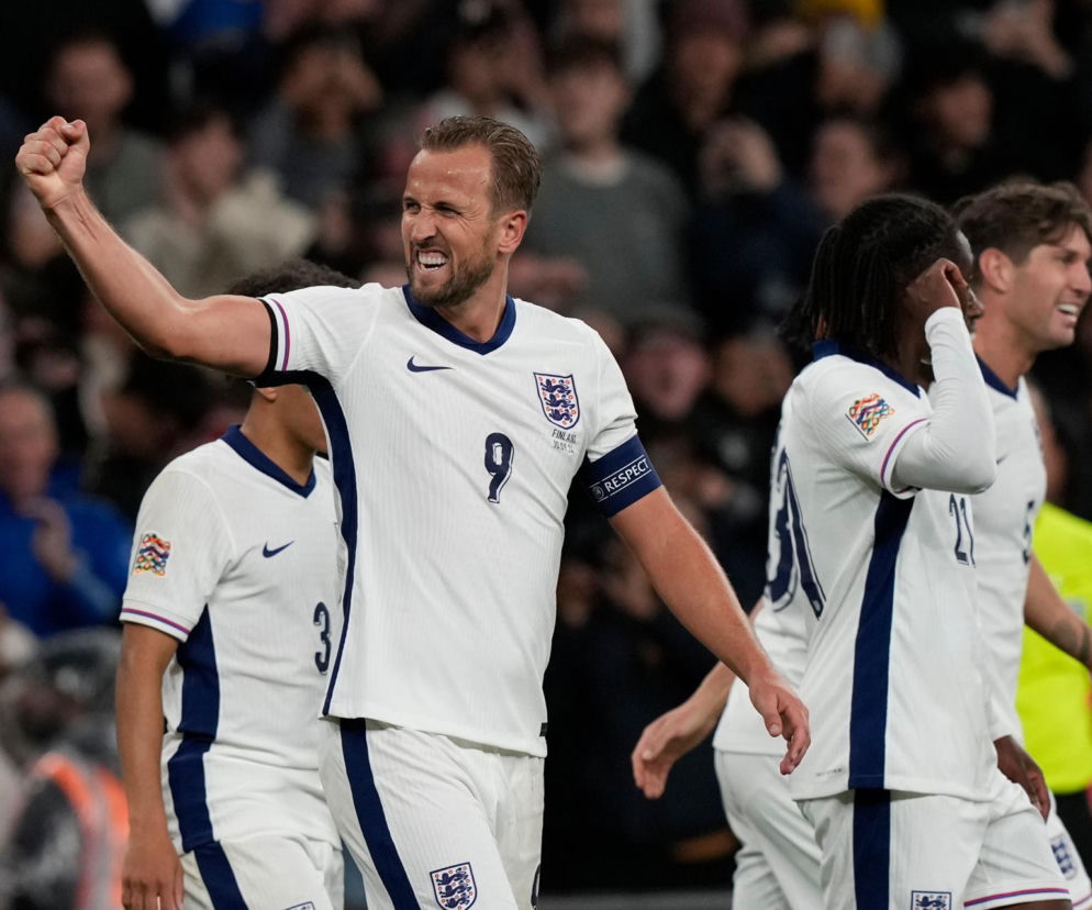 Piłkarz Harry Kane w białym stroju reprezentacji Anglii, z numerem 9, zaciska pięść po zdobytej bramce, świętując z kolegami z drużyny. O mundialu i meczach z udziałem Anglii przeczytasz więcej na naszym portalu.