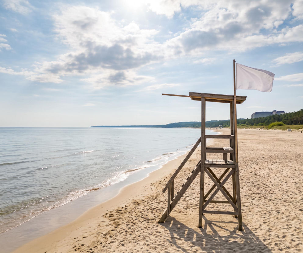 Drewniana wieża ratownicza z białą flagą na plaży w Pobierowie. O bezpiecznej kąpieli przeczytasz na SE Szczecin.