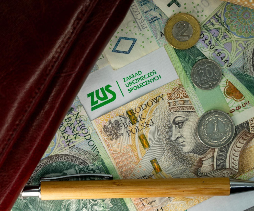 Portfel, banknoty z wizerunkami polskich władców i bilon, a także kartka z logo ZUS i długopis, ilustrujące temat zajęcia komorniczego emerytur. Szczegółowe informacje o tym, ile komornik może zabrać z emerytury, znajdziesz na Super Biznes.