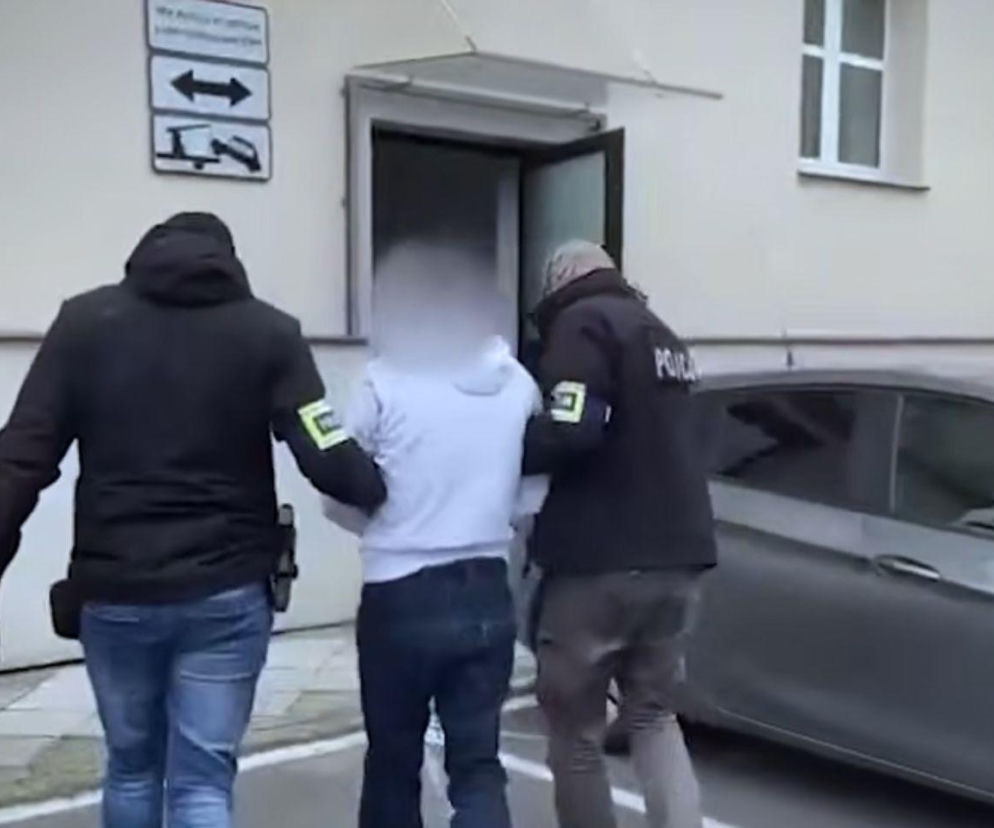 Policjanci prowadzą skutego mężczyznę z zamazaną twarzą. O kulisach zbrodni w Niedomicach przeczytasz na Mediateka.