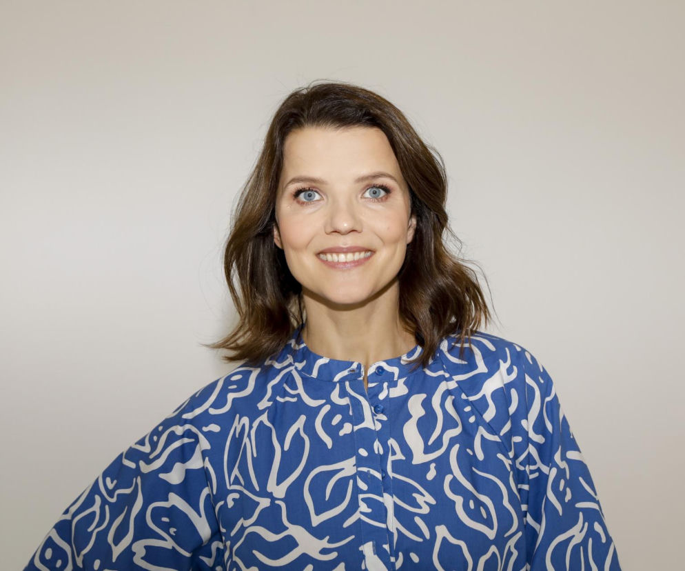 Uśmiechnięta Joanna Jabłczyńska w niebieskiej bluzce we wzory. O kulisach afery TośkaGate przeczytasz na SE.