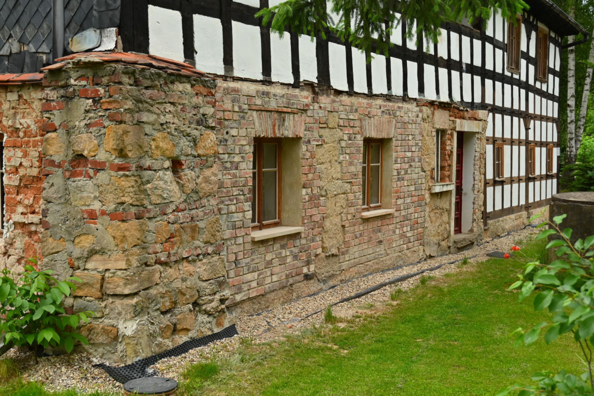 Dom w Twardocicach - remont przywraca zabytkowi dawny wygląd. Widać gruntownie wyremontowaną fasadę i zniszczoną ścianę wschodnią, na której renowację zabytek otrzymał dotację z MKiDN