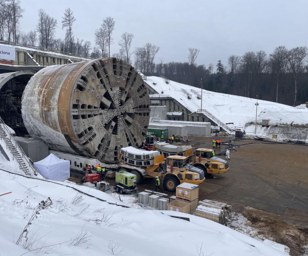 Maszyna TBM „Karpatka” na placu budowy tunelu S19 Rzeszów – Babica, gotowa do drążenia drugiej nitki. Obok pracownicy i ciężki sprzęt, w tle zaśnieżony teren. Więcej o tej inwestycji przeczytasz na portalu Architektura Murator Plus.