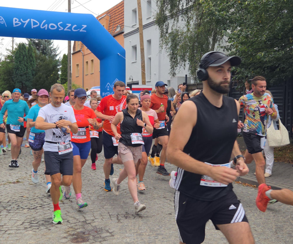 Tłum biegaczy startuje spod niebieskiej bramy z napisem Bydgoszcz. O Biegu Męczeństwa przeczytasz na Eska Bydgoszcz.
