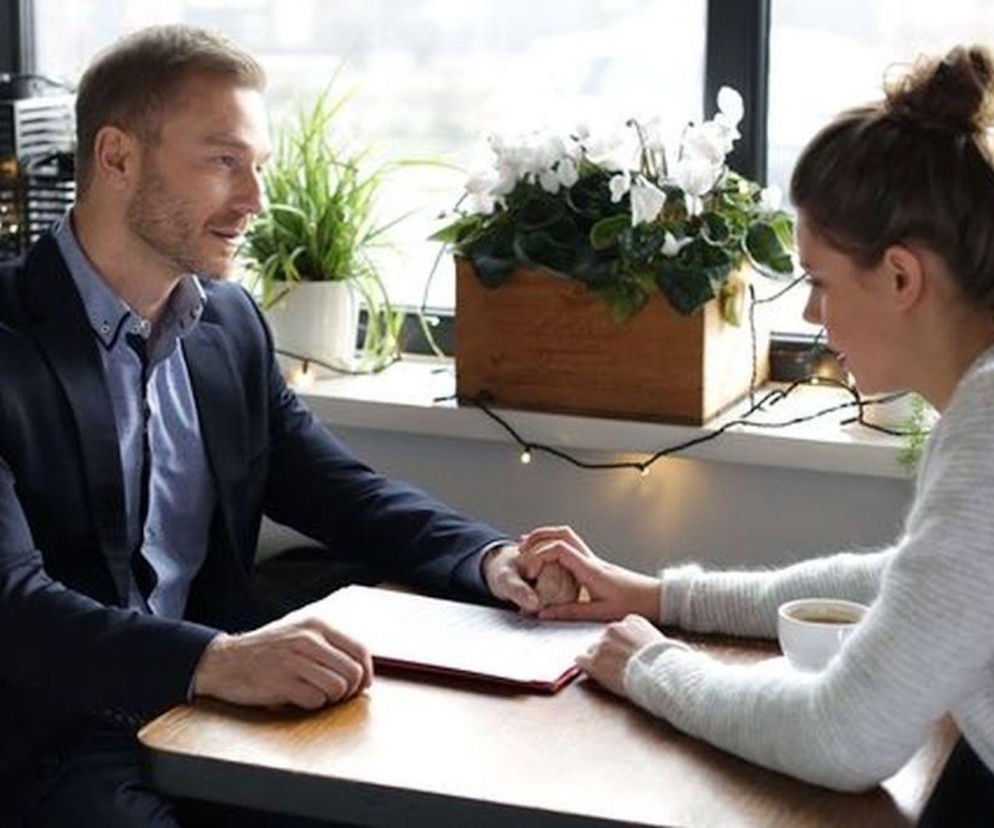 Krystian Wieczorek jako Andrzej Budzyński i Maria Wieczorek jako Paulina Lipska trzymający się za ręce przy stole. Romantyczna scena z serialu M jak miłość, gdzie była ukochana Budzyńskiego potrzebuje pomocy. Więcej o dramatycznym powrocie Pauliny na Super Seriale.