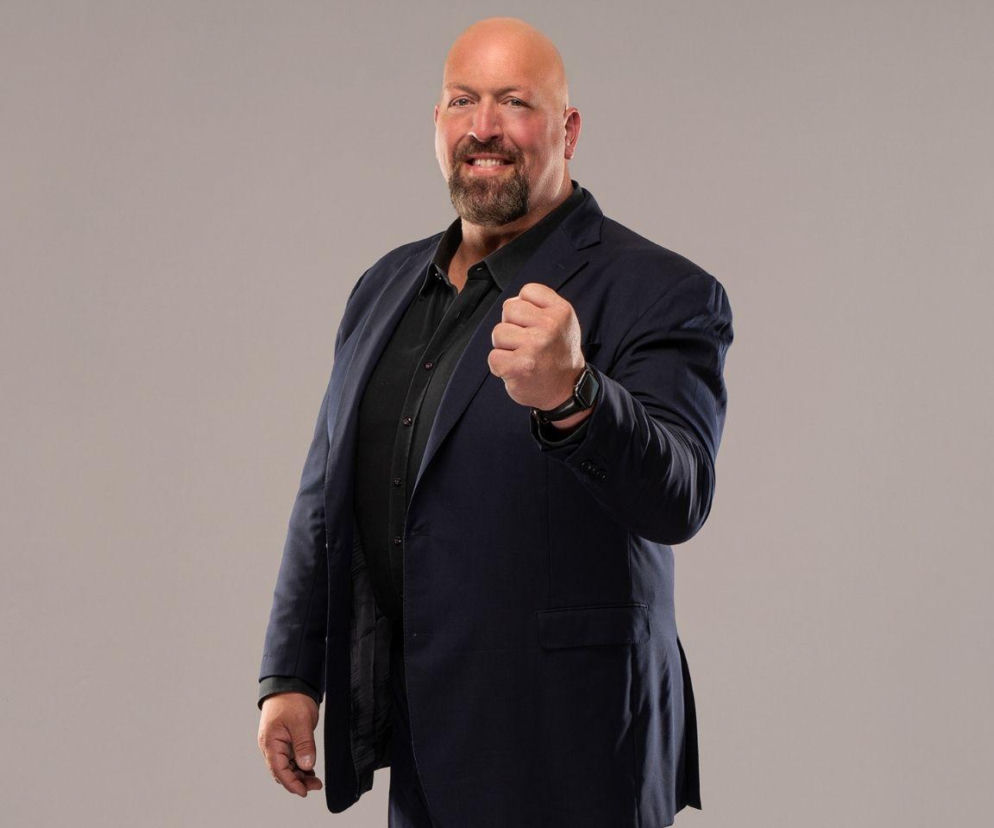 Uśmiechnięty wrestler Paul Wight w garniturze zaciska pięść. O jego planach na gale AEW w Polsce przeczytasz na SE.