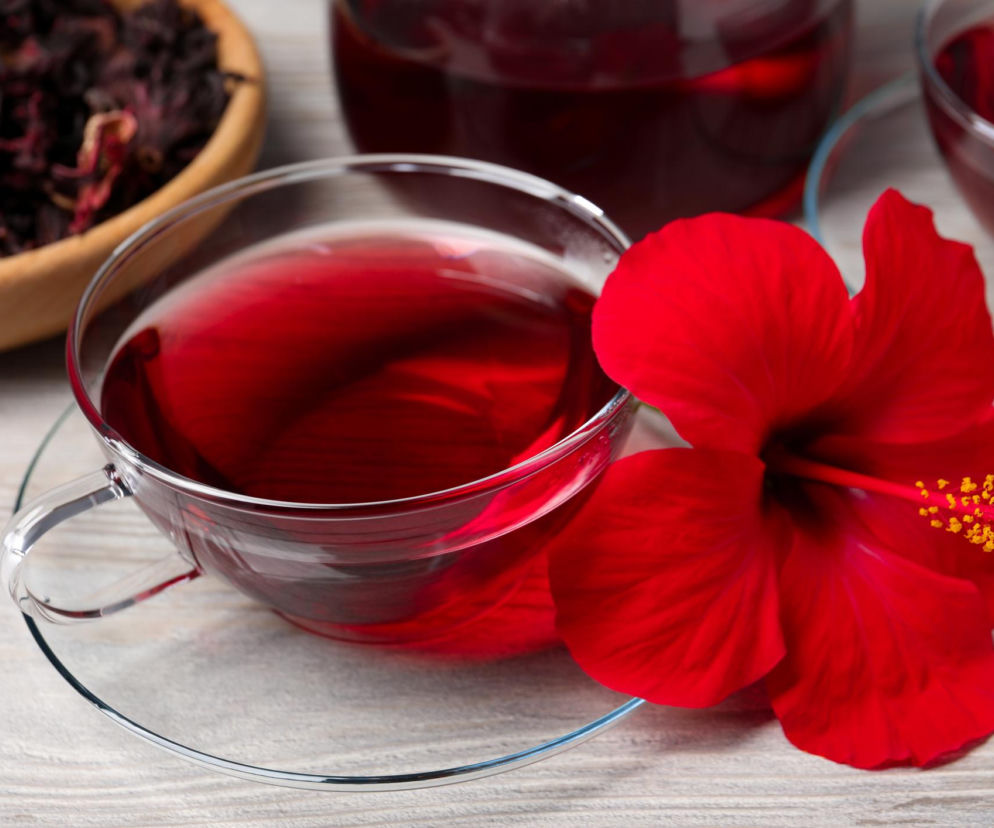 Czerwona herbata w szklance z kwiatem hibiskusa. O naturalnych sposobach na ciśnienie przeczytasz na PZ Fit.