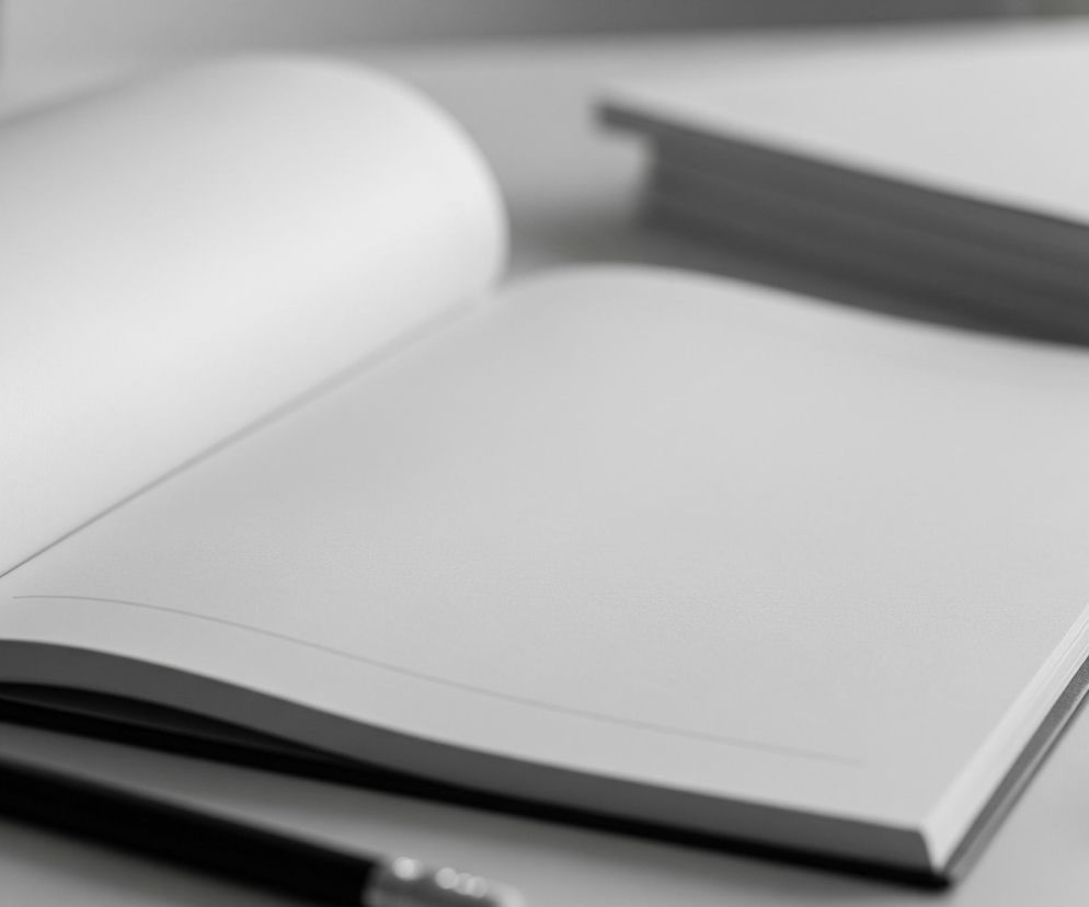 Na białym biurku leży otwarty notatnik z pustymi, białymi kartkami. Na prawej stronie notatnika znajduje się smukły, jasnoszary ołówek z zaostrzoną końcówką. W tle, po prawej stronie, widać stos trzech zamkniętych, białych notesów. Całość utrzymana jest w jasnych, neutralnych barwach, z delikatnymi cieniami podkreślającymi kształty przedmiotów.