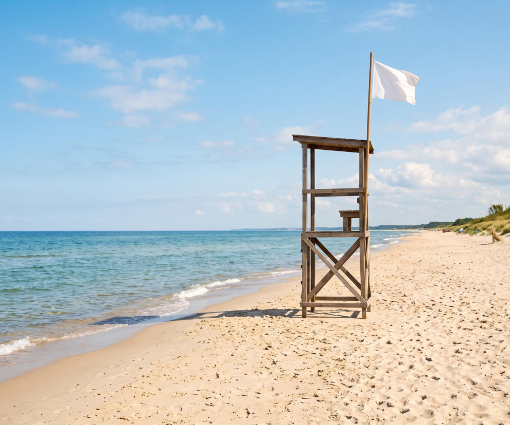 Drewniana wieża ratownika z białą flagą na pustej plaży w Sarbinowie. O bezpiecznej kąpieli przeczytasz na SE Szczecin.
