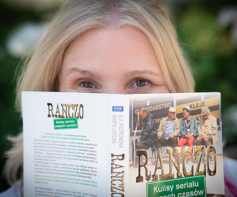 Kobieta trzymająca książkę o kulisach serialu Ranczo. O powrocie produkcji przeczytasz na Mediateka.