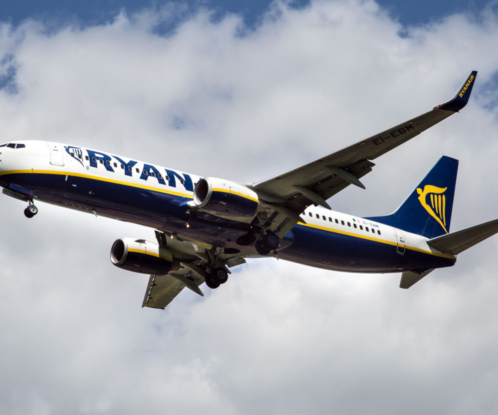 Samolot Ryanair z wysuniętym podwoziem podczas podchodzenia do lądowania na tle zachmurzonego nieba. Fotografia ilustruje artykuł o powrocie Ryanaira na Lotnisko Chopina w Warszawie oraz zapowiadanych podwyżkach cen biletów, o czym więcej przeczytasz na Super Biznes.
