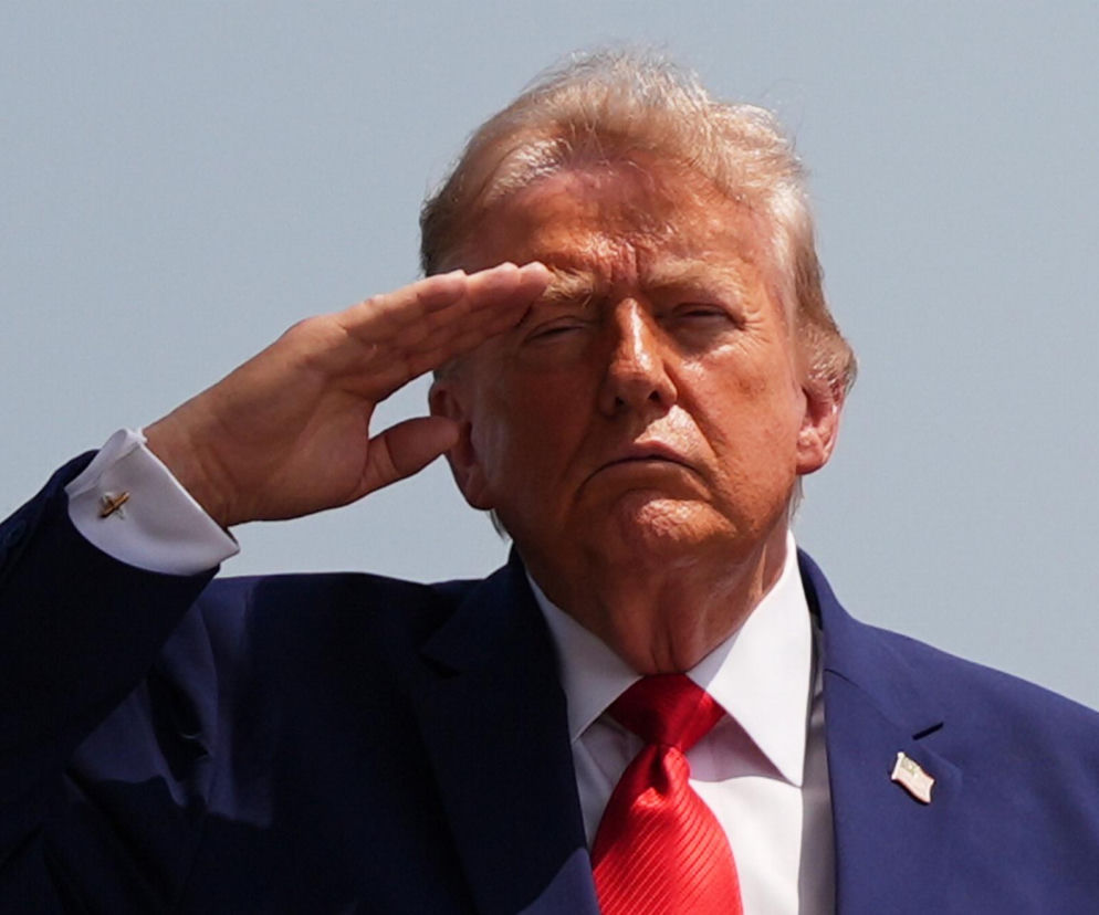 Donald Trump w garniturze salutuje z poważną miną. O jego ostrzeżeniach wobec Iranu przeczytasz w serwisie Eska.