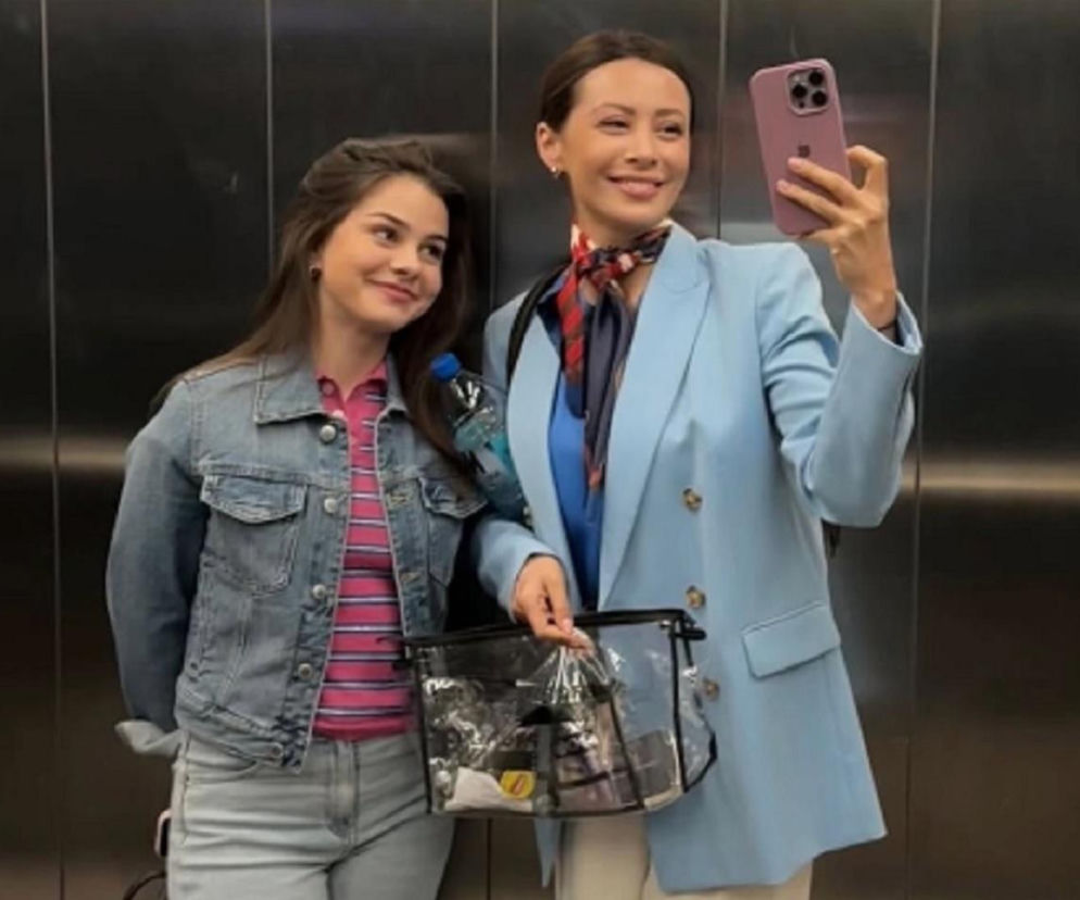 Dominika Sakowicz i Karina Woźniak uśmiechnięte pozują w windzie do zdjęcia selfie, które wykonuje Sakowicz. Obie aktorki ubrane są w casualowe stylizacje. Scena nawiązuje do serialu M jak miłość i potencjalnego rozłamu w rodzinie Mostowiaków, o czym można przeczytać na Super Seriale.