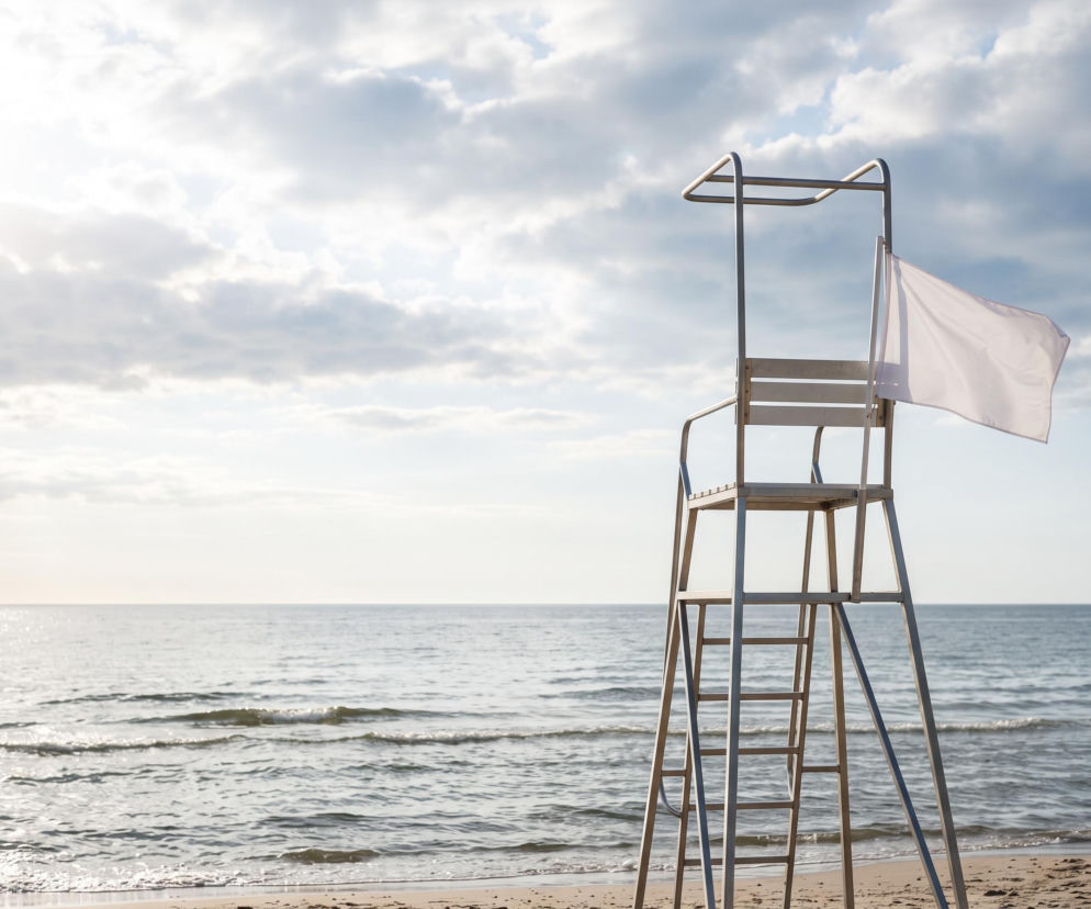 Biała flaga na wieży ratowniczej przy pustej plaży. O bezpiecznej kąpieli w Chałupach przeczytasz na Eska Trójmiasto.
