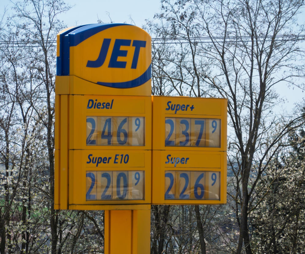 Cennik stacji paliw JET z wysokimi cenami za diesel (2,46 euro), Super+ (2,37 euro), Super E10 (2,20 euro) i Super (2,26 euro) w Niemczech. Widoczne drzewa w tle. Aktualne informacje o cenach paliw na Super Biznes.