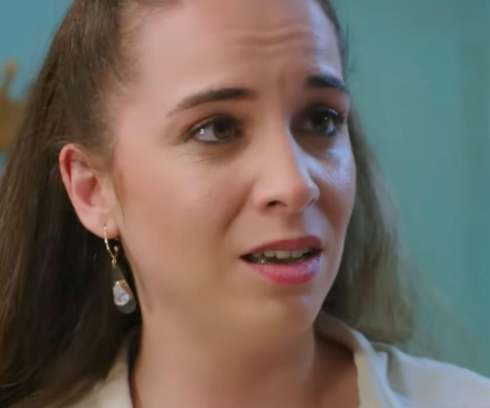 Kadr z tureckiego serialu Panna młoda, przedstawiający Beyzę (Çisel Kuskan) z zaniepokojoną miną, w jasnej bluzce i kolczykami, na tle turkusowej ściany. Więcej o zniknięciu Beyzy znajdziesz na Super Seriale.