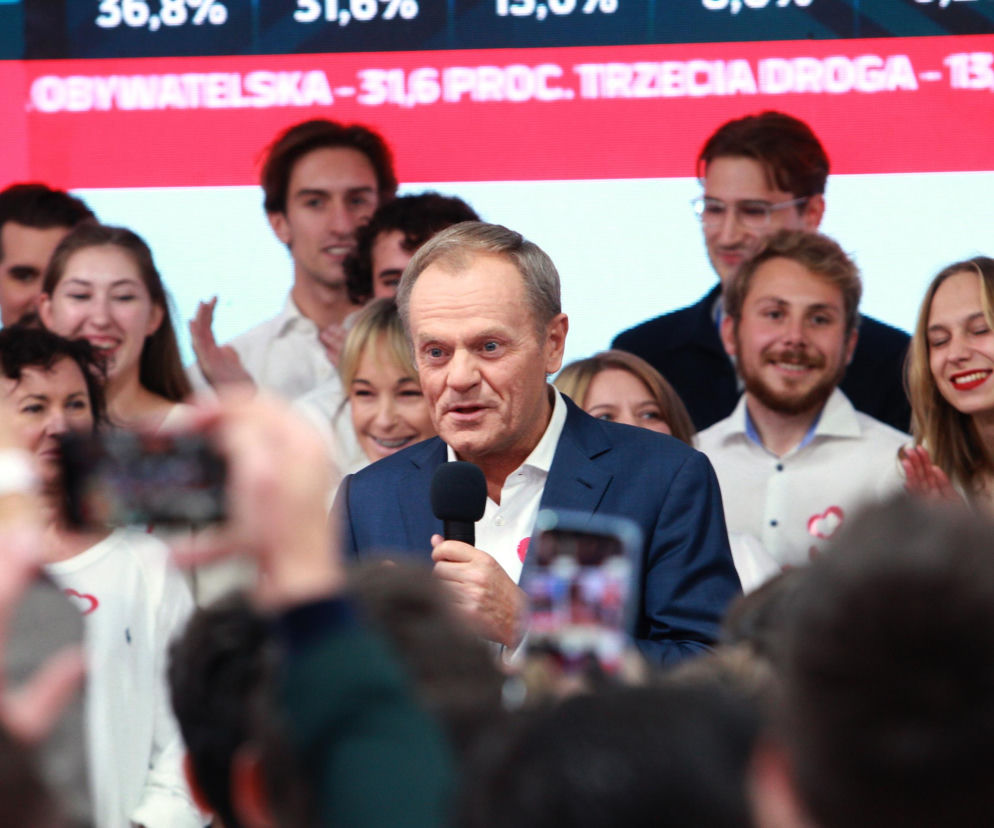 Donald Tusk z mikrofonem na tle wiwatujących ludzi. O realizacji 100 konkretów KO przeczytasz na SE Superbiz.