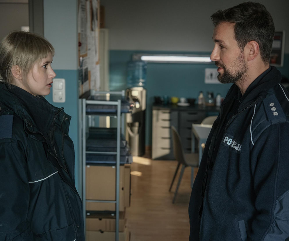 Daria (Anna Michalska) i Marcin (Oskar Stoczyński) w policyjnych mundurach, stojący naprzeciwko siebie i rozmawiający wewnątrz budynku. Nowa kobieta w życiu Marcina w serialu Barwy szczęścia dostępnym na Super Seriale.