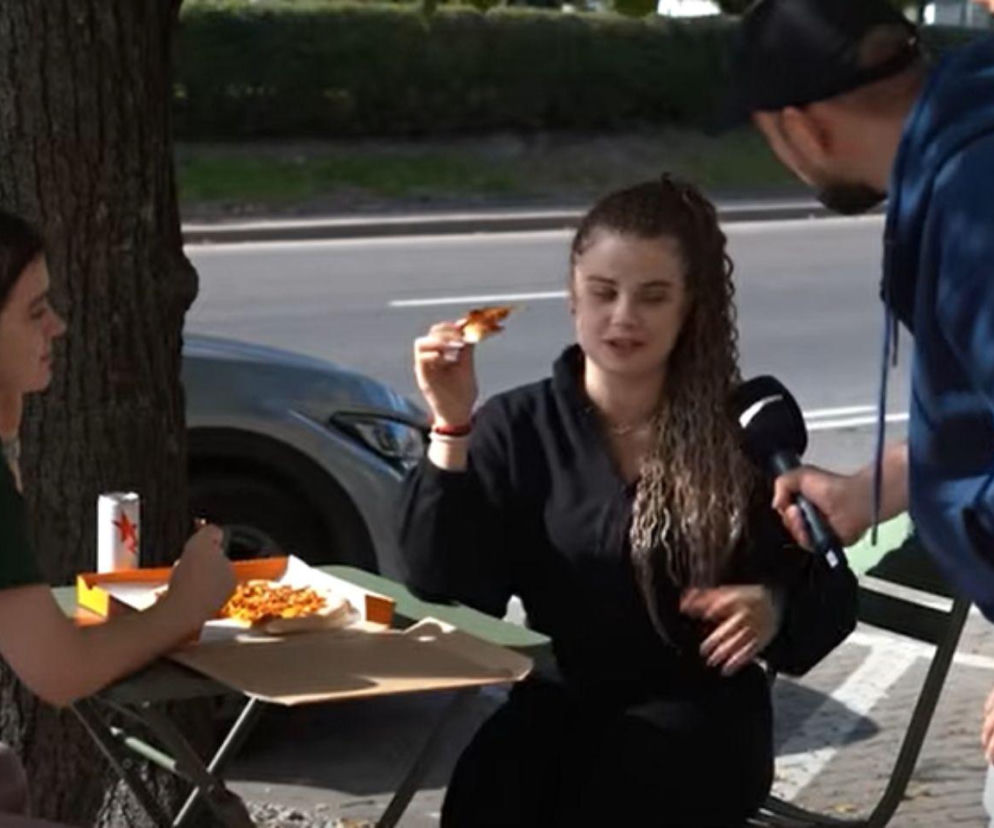 Adam Feder rozmawia z kobietą jedzącą pizzę na ulicy Siemiatycz. O końcu emigracji do Belgii przeczytasz na Mediateka.