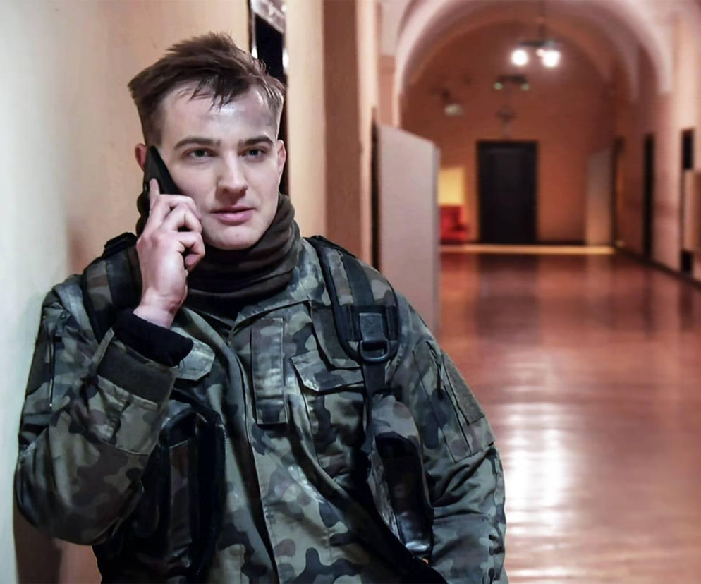Kamil Biały w mundurze rozmawia przez telefon na korytarzu. O losach bohatera przeczytasz na SE Superseriale.