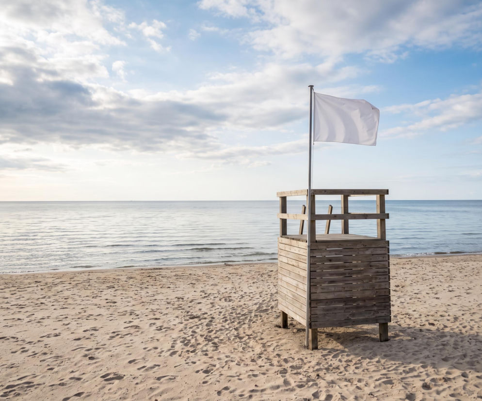 Drewniana wieża ratownicza z białą flagą na pustej plaży w Sarbinowie. O bezpiecznej kąpieli przeczytasz na SE Szczecin.